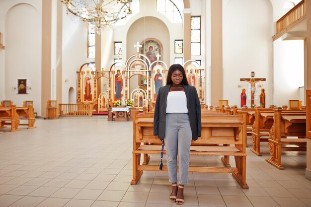 African american woman praying in the church Believers meditates in the cathedral and spiritual time of prayer Afro girl with rosary on hands