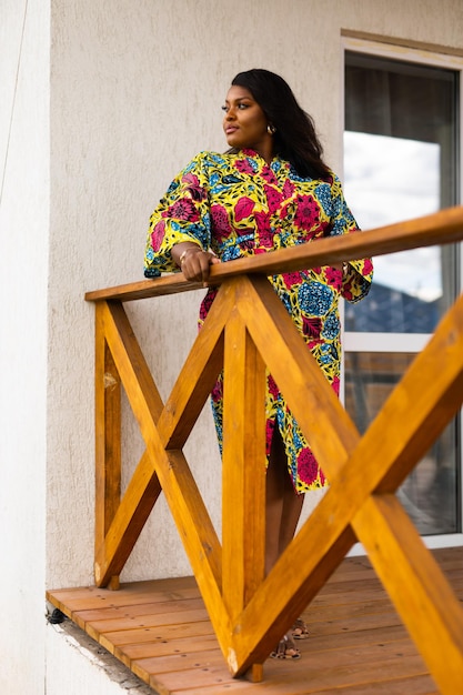 Foto donna afroamericana che si rilassa e si gode il sole stando in piedi sulla terrazza o sul balcone alla luce del sole