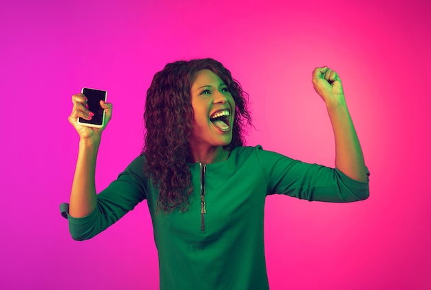 African-american woman's portrait on pink background in neon