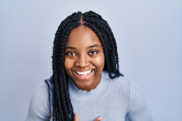 African american woman standing over blue background smiling and laughing hard out loud because funny crazy joke with hands on body.