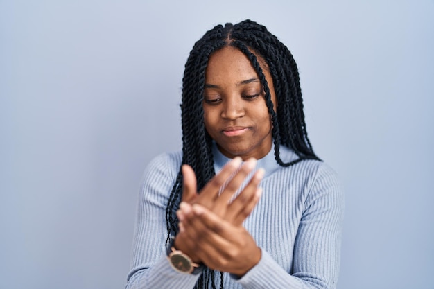 African american woman standing over blue background suffering pain on hands and fingers arthritis inflammation