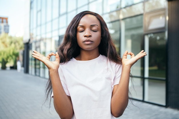 Афро-американская женщина стоит снаружи и медитирует