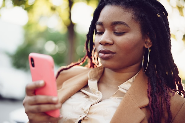 African american woman standing in a street and using smartphone