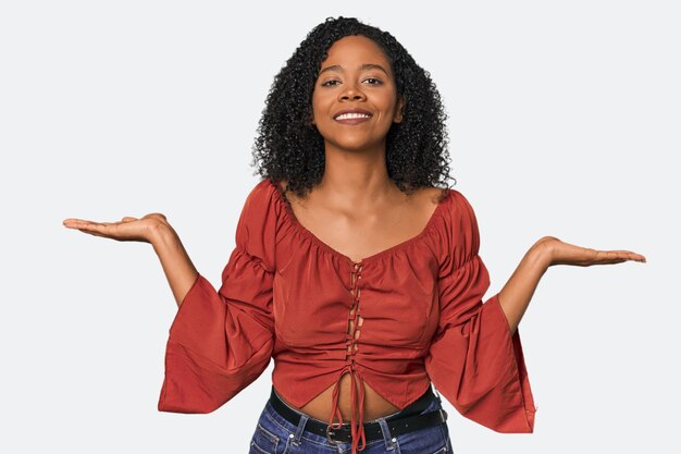 Photo african american woman in studio setting makes scale with arms feels happy and confident