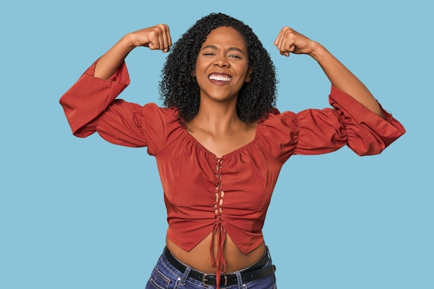 African American woman in studio setting showing strength gesture with arms symbol of feminine power