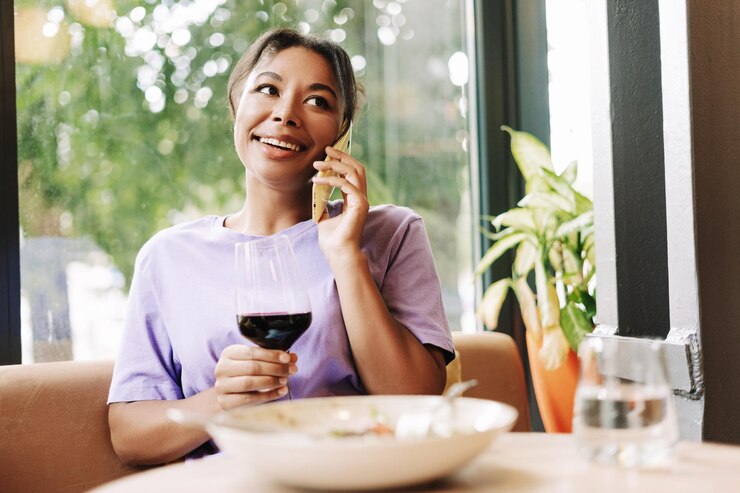Photo アフリカ系アメリカ人の女性が電話で話しレストランでワインを飲み電話に対応しています