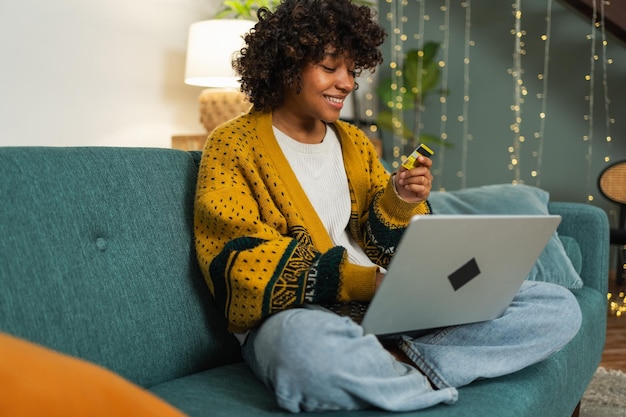 Photo african american woman using laptop shopping online paying with gold credit card girl sitting at