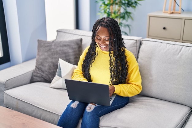 African american woman using laptop sitting on sofa at home