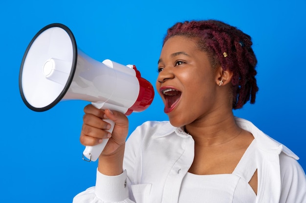 Photo african american woman using megaphone against blue background