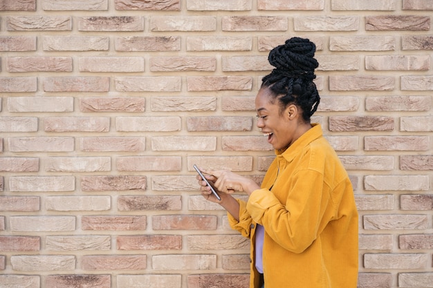 Donna afroamericana che utilizza il telefono cellulare per lo shopping online con le vendite ispirazione black friday