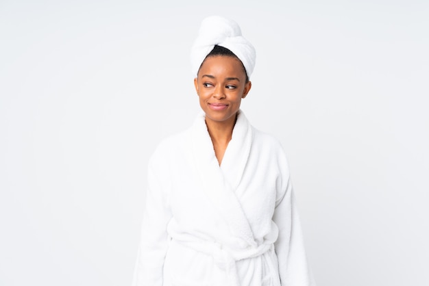 African American woman wearing bathrobe over white wall