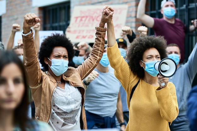 African American woman wearing protective face masks and holding hands while participating in demonstrations for human rights on the streets