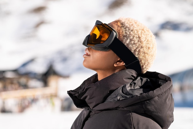 An African American woman wearing snow goggles on a snowy mountain during winter