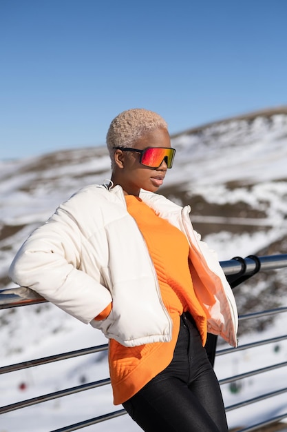 An African American woman wearing snow goggles on a snowy mountain during winter