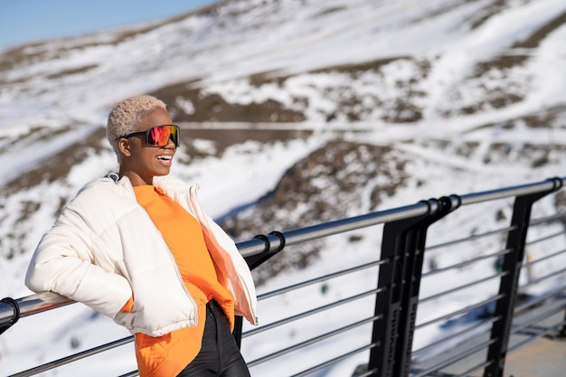 An African American woman wearing snow goggles on a snowy mountain during winter