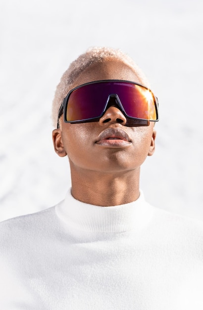 An African American woman wearing snow goggles on a snowy mountain during winter