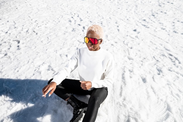 An African American woman wearing snow goggles on a snowy mountain during winter