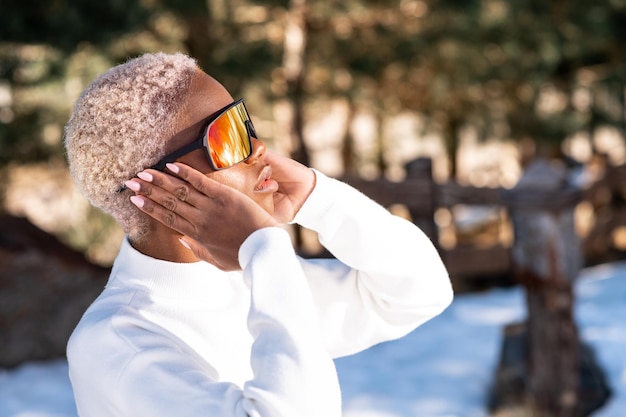 An African American woman wearing snow goggles on a snowy mountain during winter