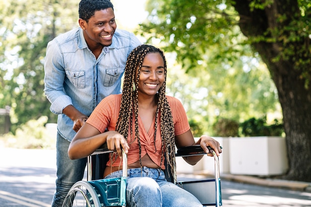 An african american woman in a wheelchair enjoying a walk with her boyfriend.