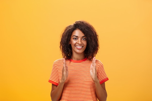 Афро-американская женщина с афро-прической показывает размер руками и улыбается в камеру