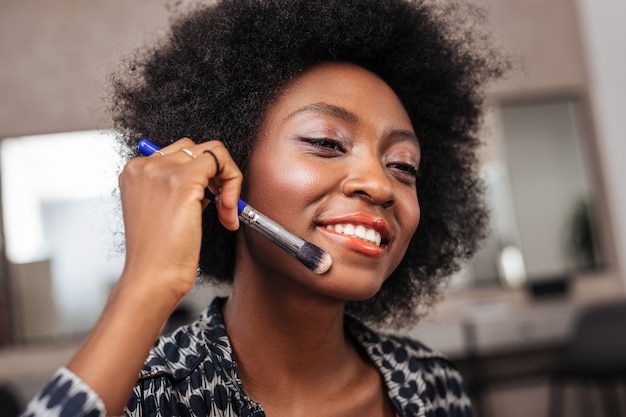 African american woman with curly hair looking positive while recording video