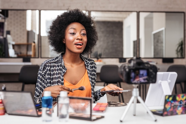 African american woman with curly hair looking positive while recording video