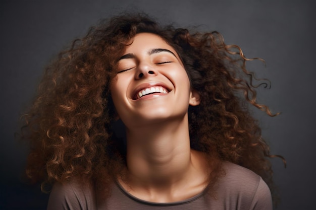 An African American woman with curly hair smiles and her eyes closed