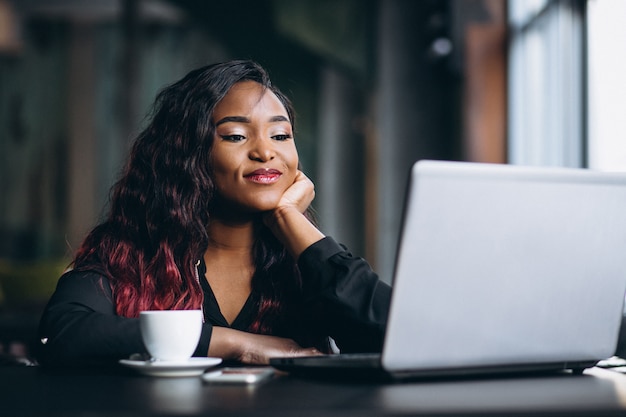 Donna afro-americana con laptop e caffè