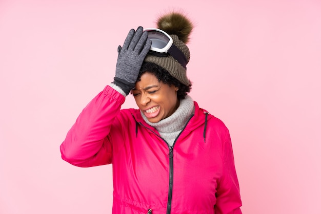 African American woman with snow goggles over pink wall