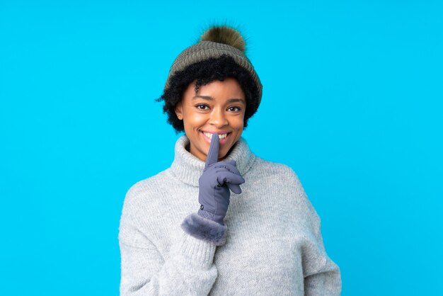 African American woman with winter hat over isolated blue wall