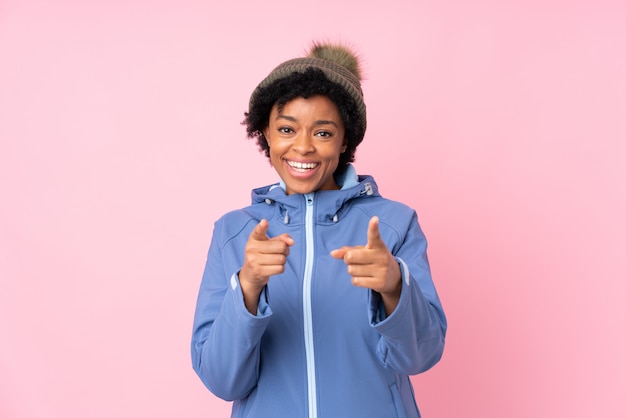 African American woman with winter hat over pink wall