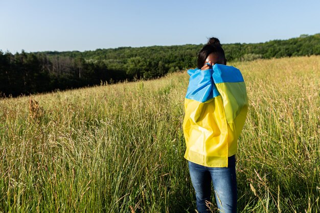 Африканская американка, завернутая в украинский желто-голубой флаг, национальный символ Украины