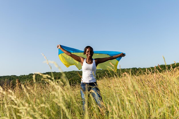 ウクライナの黄青旗ウクライナの国家シンボルに包まれたアフリカ系アメリカ人の女性