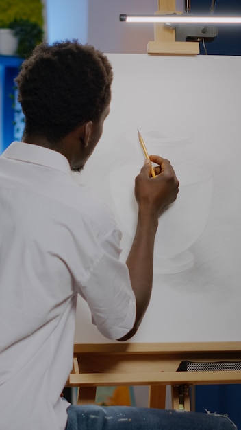 African american young adult using pencil on canvas drawing