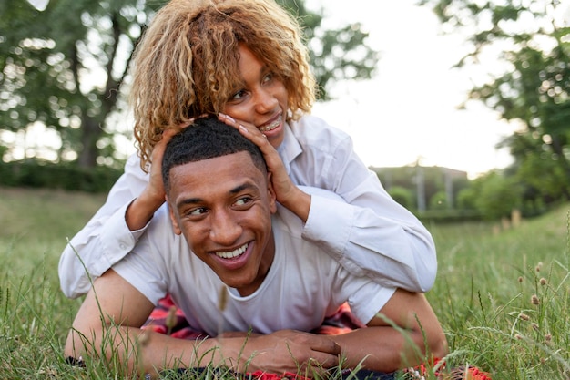 사랑에 빠진 아프리카계 미국인 젊은 부부는 여름에 공원의 잔디에 함께 누워 웃는다.