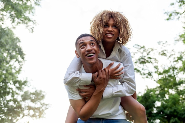 Молодая афроамериканская пара, влюбленная, бежит вместе в парке летом и улыбается.