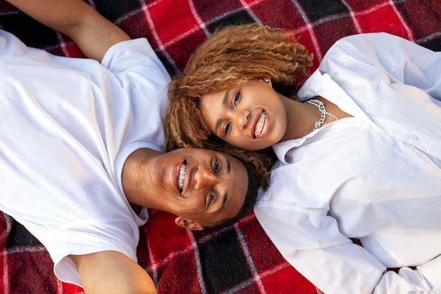 African american young couple lying on blanket and looking up and smiling man and woman relaxing