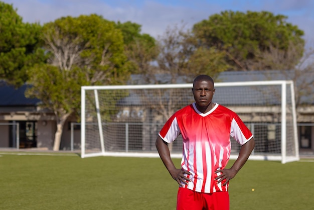 African American young male athlete standing on soccer field outdoors hands on hips copy space