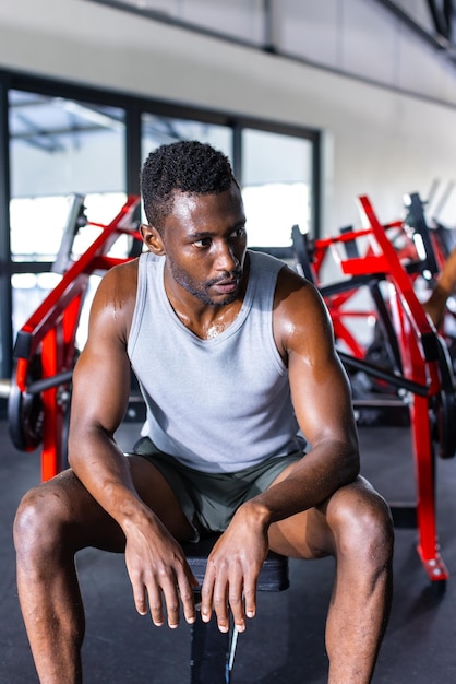 African American young male athlete wearing a tank top and shorts resting in gym