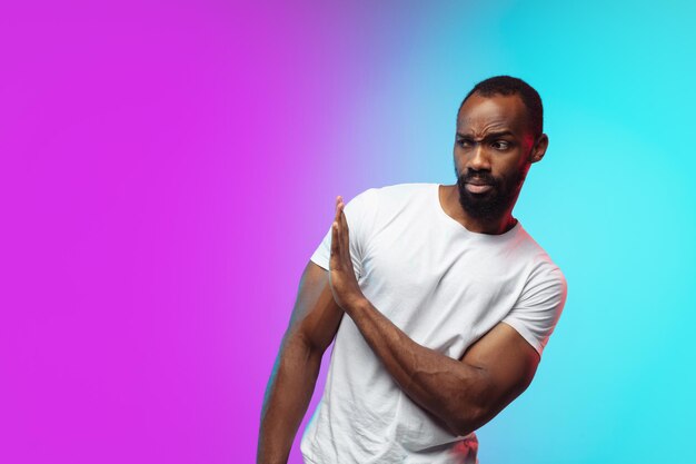 African-american young man's portrait on gradient studio background in neon