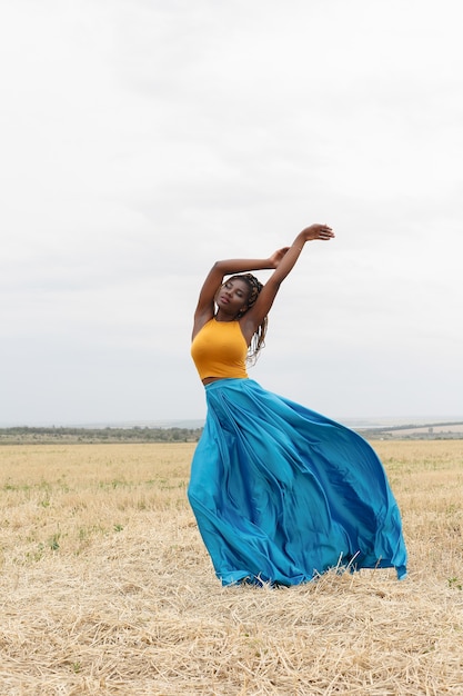 African american young woman having fun outdoors at sunset. laughing girl on field. beautiful young african american woman with pigtails