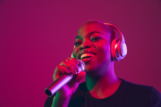 African-american young woman's portrait on purple pink background in neon