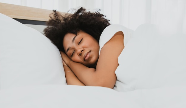 Фото Афро-американская молодая женщина хорошо спит в белой постели. сон для здоровья