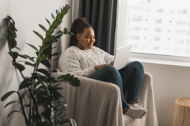 African american young woman using laptop on chair technologies and communication and social network concept