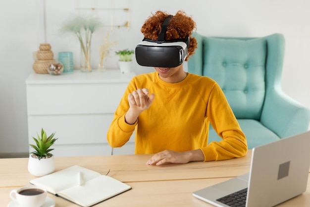 Photo african american young woman wearing using virtual reality metaverse vr glasses headset at home girl