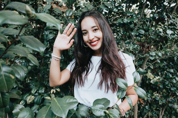 African arab young girl between green leaves smiling and saluting to camera. Natural isolated. Social network day at nature concept. Beauty portrait. Copy space for text and adds. Health.