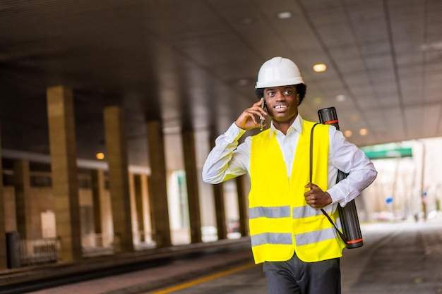 Photo african architect talking to the mobile while walking outdoors