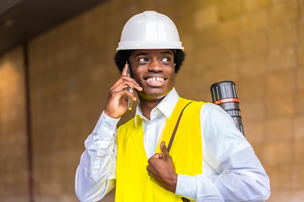 Photo african architect talking to the phone while visiting construction site