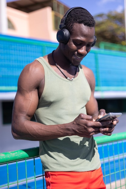 African athlete looking at his cell phone on the athletics track