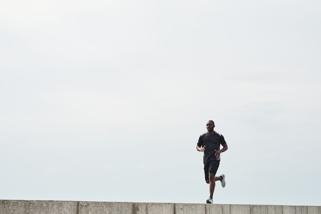 African athlete running in the morning outdoors against the blue sky